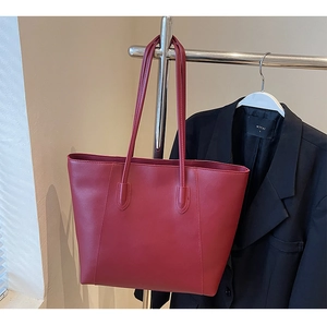 Detail of burgundy leather tote bag with slim shoulder straps and premium stitching