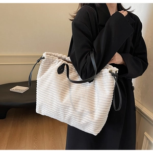 Detail of white corduroy tote bag with black leather straps and striped texture