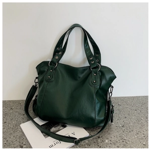 Detailed view of deep green tote bag with silver studs and adjustable shoulder strap