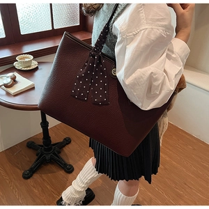 Detail of burgundy tote bag with lychee texture and decorative brown polka dot scarf