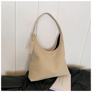 Détail d'un grand sac hobo en cuir beige avec bandoulière minimaliste et étiquette latérale