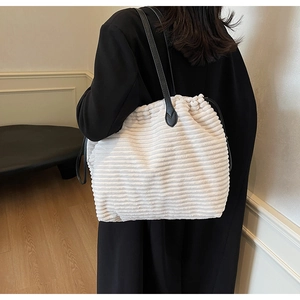 Close-up detail of cream corduroy tote bag with drawstring closure and black leather straps