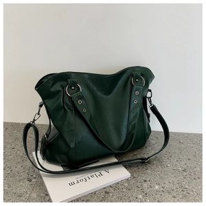 Detailed close-up of dark green faux leather tote bag with silver metal ring hardware