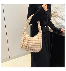 Detail of beige quilted cloud bag showing soft puffy texture and integrated shoulder strap