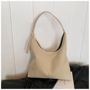 Gros plan d'un sac hobo en cuir mat beige avec coutures verticales et étiquette pendante
