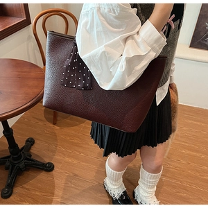 Detail of dark red lychee texture tote bag with a polka dot silk scarf on the handle