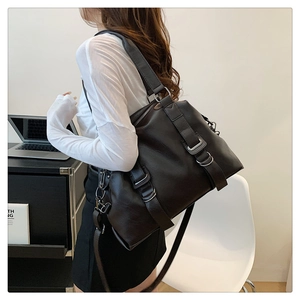 Detail of dark faux leather tote bag with wide shoulder strap and decorative buckle