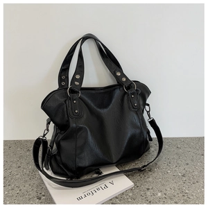 Detail of black large capacity faux leather tote bag with silver metal rings and rivets
