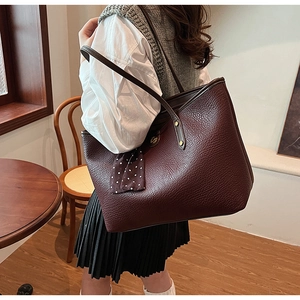 Detail of burgundy leather tote bag with polka dot scarf on model's shoulder
