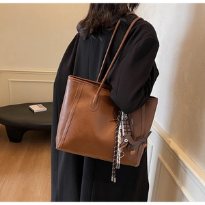 Detailed view of dark brown leather tote bag with unique dachshund and chocolate charms