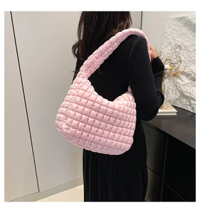 Detail of pink quilted puffy shoulder bag showing soft pleated texture and wide strap