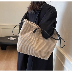 Detail of corduroy tote bag featuring beige texture and black shoulder straps
