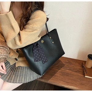 Close-up of black lychee leather tote bag with polka dot silk scarf detail on shoulder