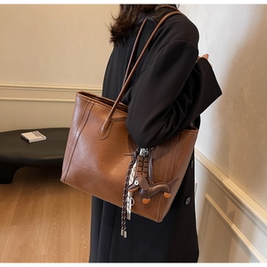Close-up of brown faux leather tote bag featuring a cute dachshund and chocolate charm