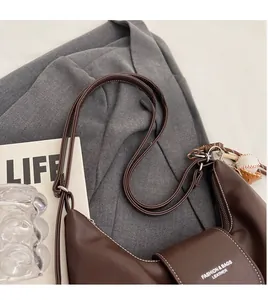 Detail view of dark brown faux leather hobo bag with white stitching and fashion logo
