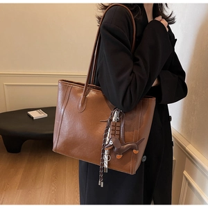Detail of a large brown leather tote bag with creative dachshund and chocolate charms
