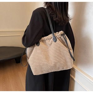 Detail of soft corduroy tote bag with drawstring closure and leather straps on model