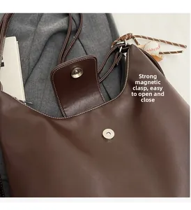 Close-up of secure magnetic snap closure on a dark brown faux leather tote bag