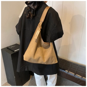 Gros plan d'un grand sac hobo kaki en daim porté à l'épaule pour femme