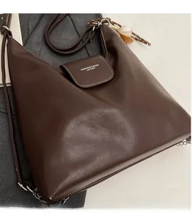 Detail of dark brown leather tote bag showing smooth texture and baseball charm