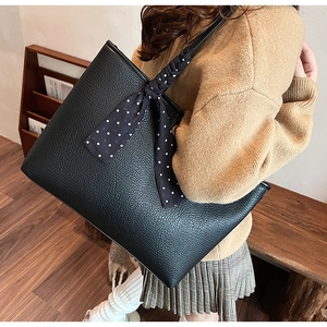 Detail of black pebbled leather tote bag with stylish blue polka dot scarf decoration