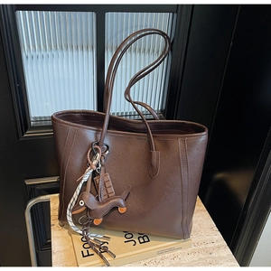 Detail of dark brown tote bag with leather texture and cute dachshund dog pendant decoration