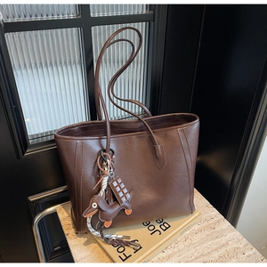 Detail of dark brown leather tote bag with a chocolate bar and dachshund dog charm