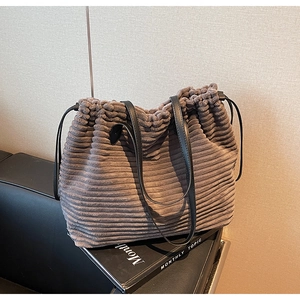 Detail of grey corduroy tote bag with drawstring closure and black leather straps