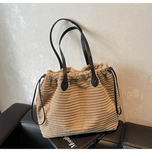 Close-up of corduroy tote bag with drawstring closure and black leather strap detail