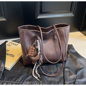 Detail of dark brown leather tote bag with chocolate and puppy charms on black leather