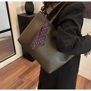 Detailed macro view of olive green lychee grain leather tote bag with decorative scarf