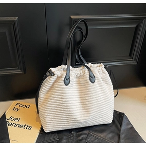 Detail of cream corduroy tote bag with black leather handles and adjustable drawstring closure