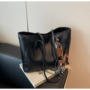 Detail of black faux leather tote bag with cute chocolate and dachshund charms