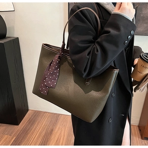 Detailed view of olive green textured leather tote bag with elegant polka dot scarf accessory