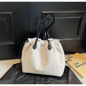 Detail of white corduroy tote bag with black leather straps and side drawstring closure