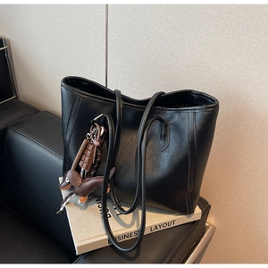 Detail of black leather tote bag with decorative stitching and cute animal charms