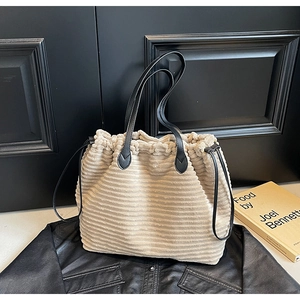 Detail of beige corduroy tote bag with black leather straps and drawstring closure