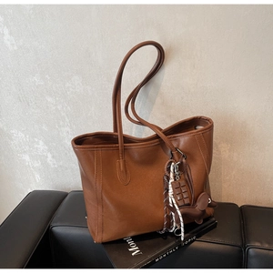 Detail of a brown tote bag with smooth faux leather texture and a cute puppy charm