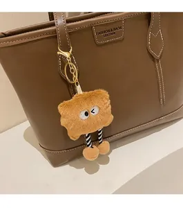 Détail d'une peluche de monstre marron suspendue à un grand sac cabas vintage chic