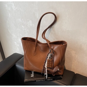 Detailed close-up of brown faux leather tote bag with cute chocolate and puppy charms