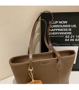 Gros plan d'un cabas en cuir PU marron avec bandoulière et pendentif en pompon doux