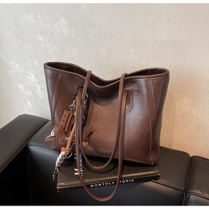 Detail of dark brown tote bag with leather texture and dachshund shaped charm