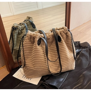 Detail of corduroy tote bag featuring leather drawstring closure and striped texture