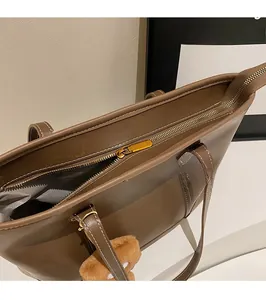 Détail d'un sac cabas marron avec fermeture éclair dorée et pendentif ours en peluche