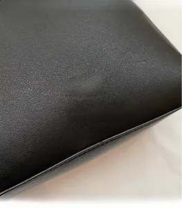 Détail de cuir noir à motif litchi avec logo doré pour un sac à bandoulière seau