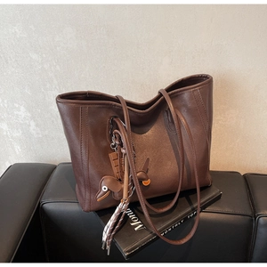 Detail of dark brown faux leather tote bag with cute dog doll and chocolate pendant charms