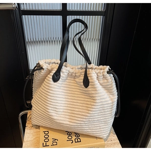 Close-up of white corduroy tote bag with black leather handles and drawstring detail