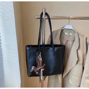 Detail of black faux leather tote bag with unique dachshund charm and tassel accessory