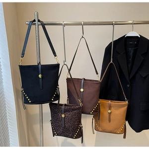 Detail view of stylish leopard print and suede bucket bags with metallic rivet accents
