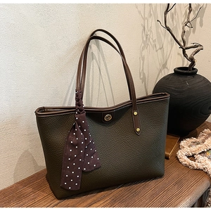 Detail of olive green pebbled leather tote bag with polka dot scarf and golden logo